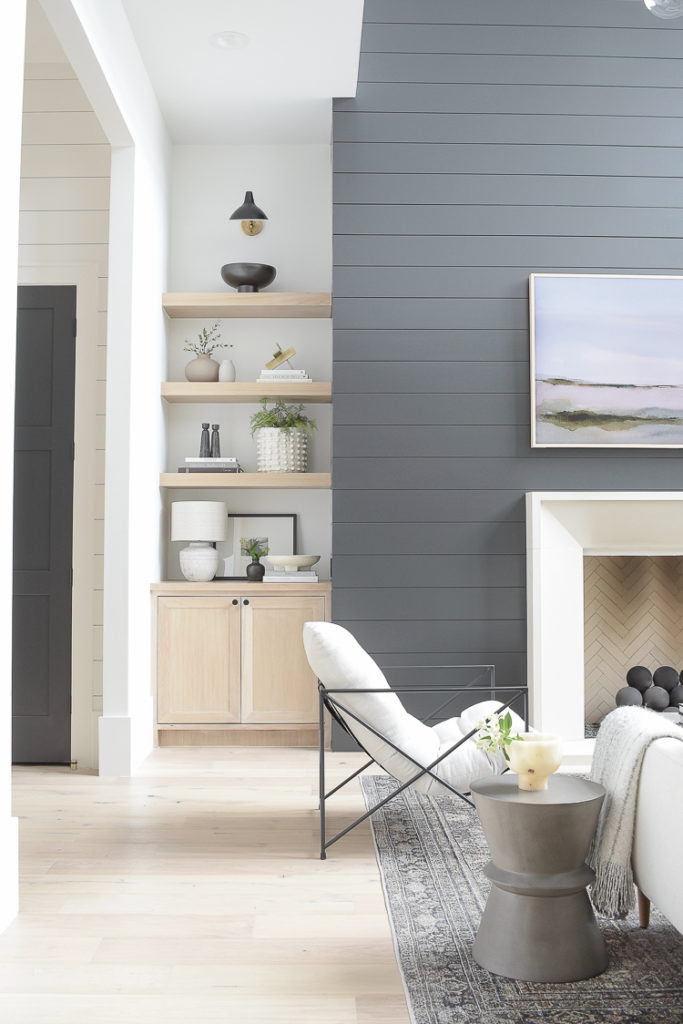 white oak shelves decorated in modern living room with black shiplap fireplace