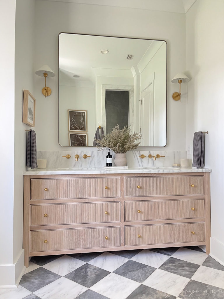 fluted drawers on vanity in gorgeous master bathroom with checkered floors and brass fixtures