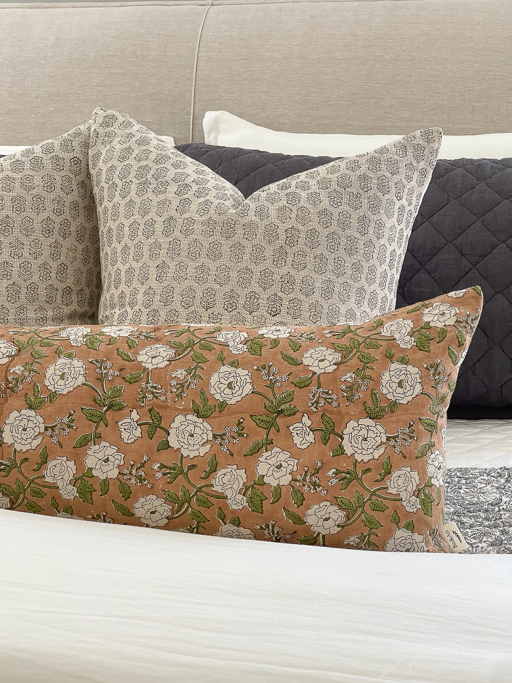 block and floral print pillows on bed 