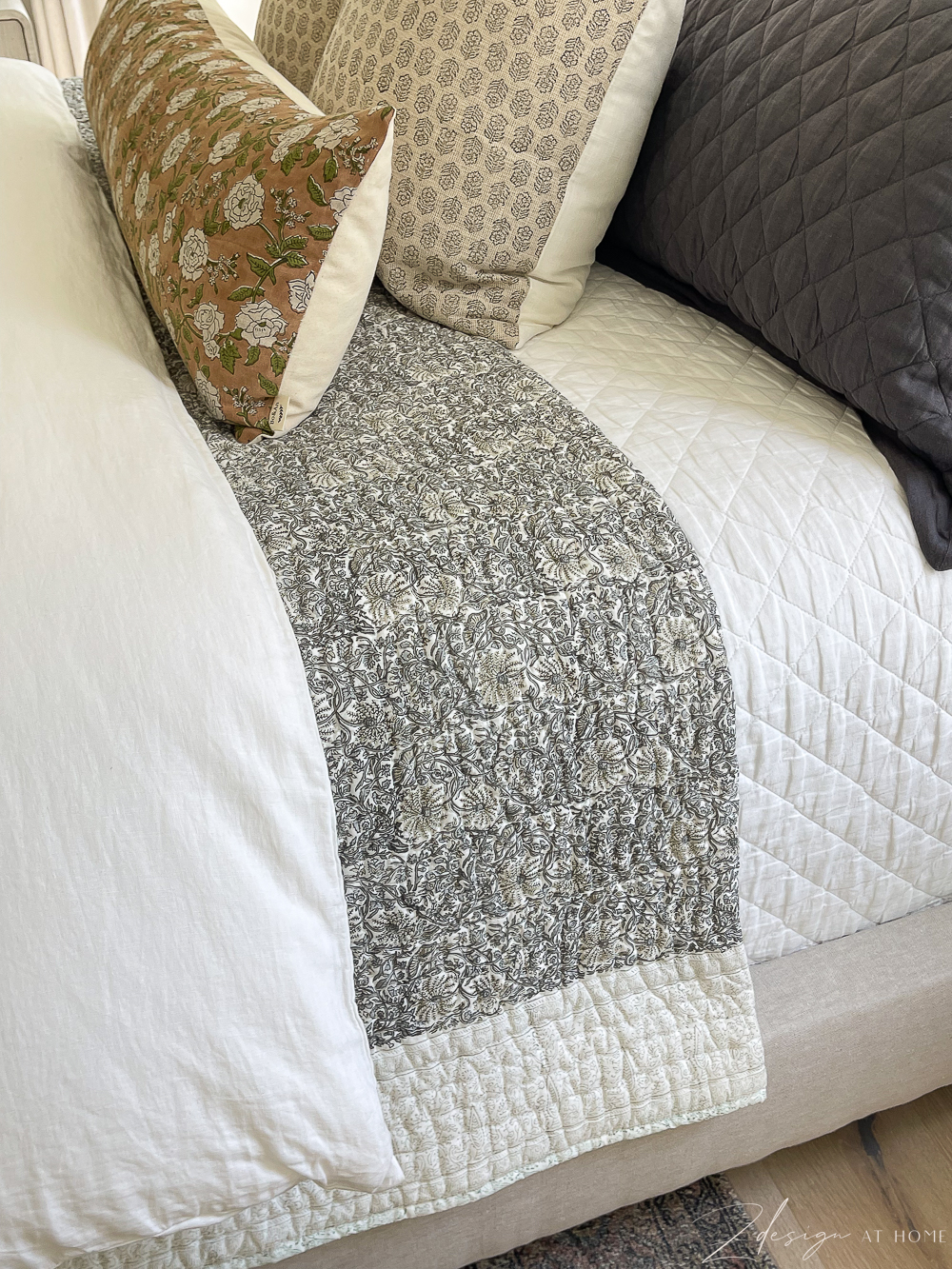 floral block print quilt layered on neutral bed with white linen diamond quilt 