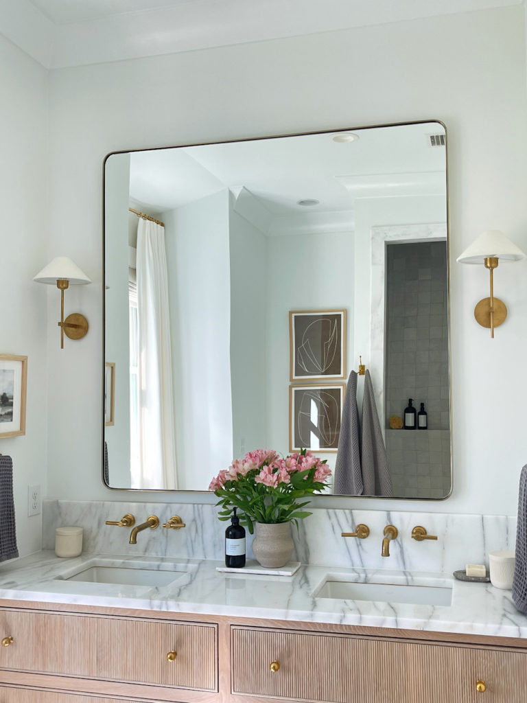 oversized brushed brass mirror with marble countertop, Kohler sinks and brass wall mounted faucets 