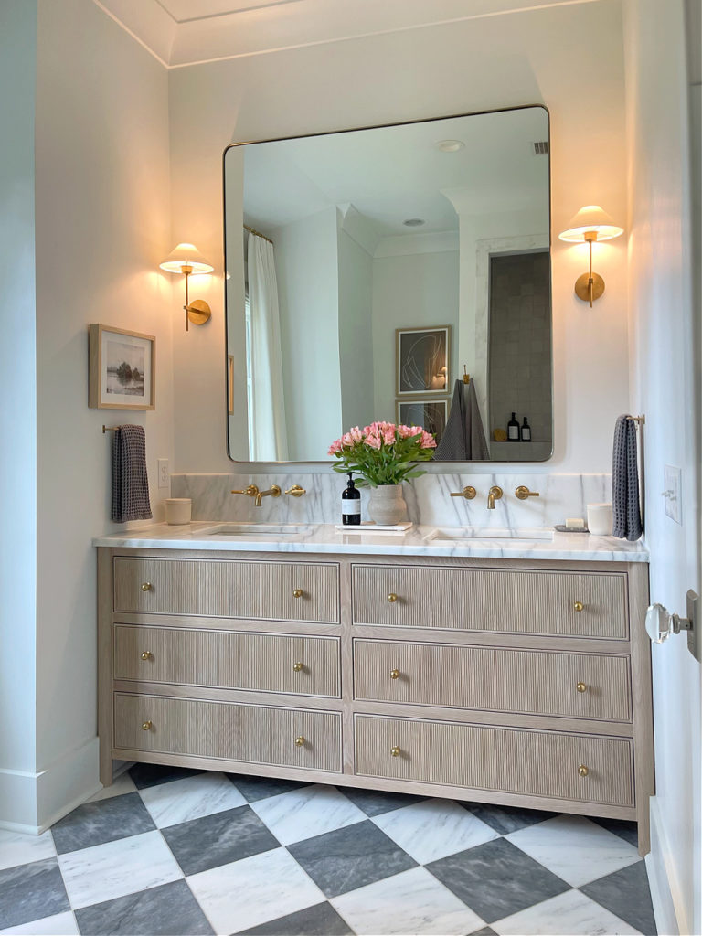 reeded fluted vanity, white marble, checkerboard floors, 8" backsplash with wall mounted faucets in primary, master bath