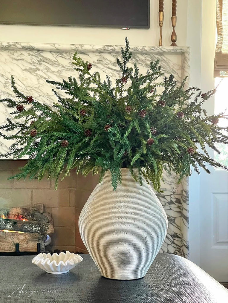 gray ribbed vase with norfolk pine branches and pinecone stems on black coffee table for Christmas decor 