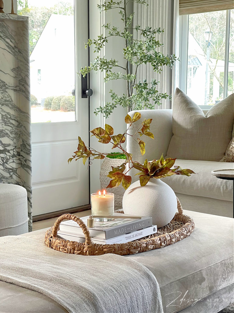 coffee table ottoman upholstered styled with handle basket tray, books, candle and fall to spring stems 