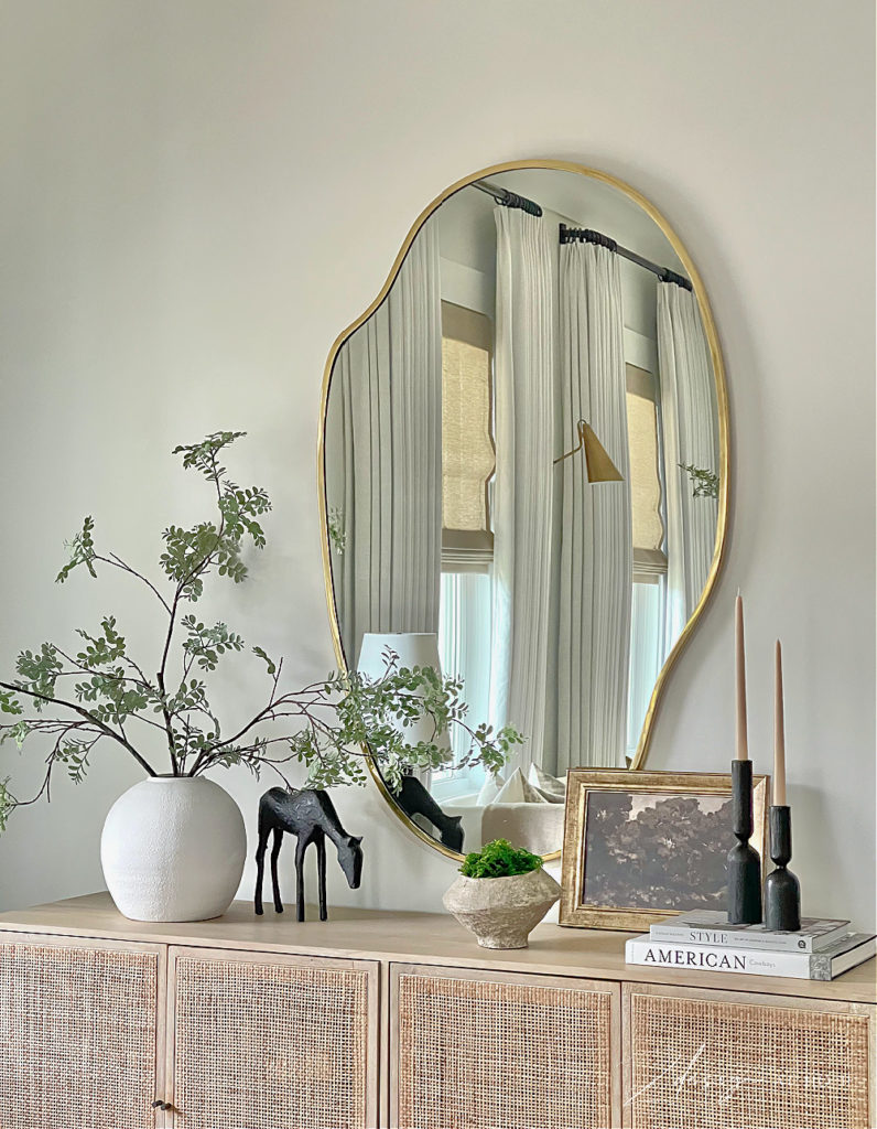 vignette styled for winter/ early spring.  brass puddle mirror, white texture vase, black horse statue figure, moody art, how to style your console or entryway / foyer 